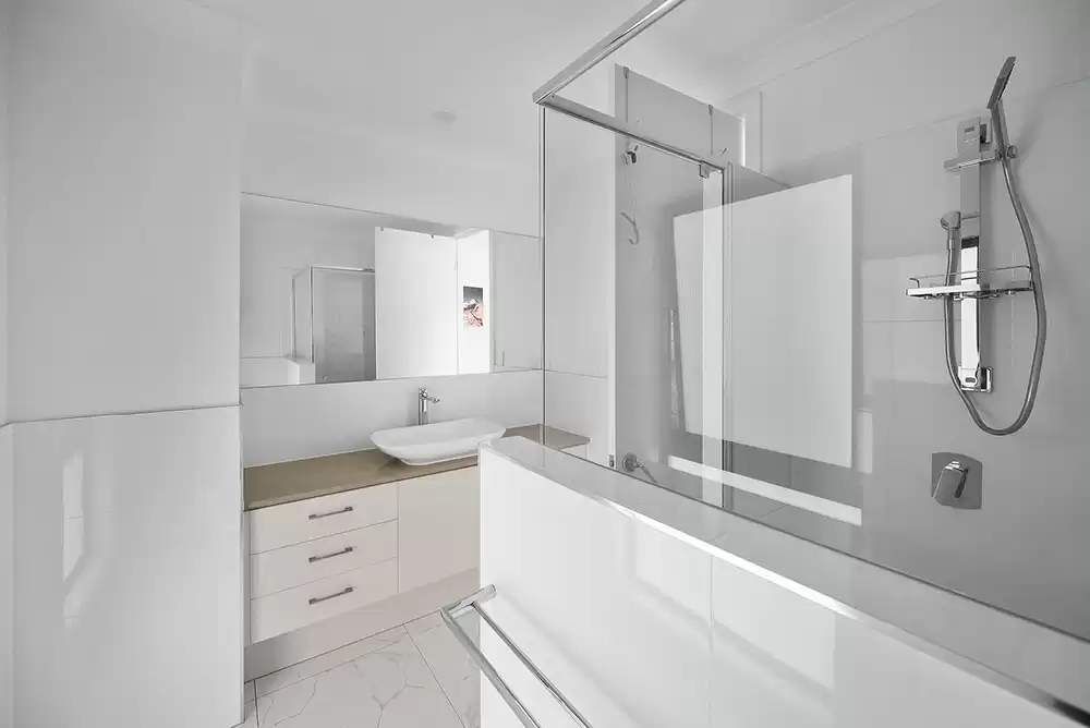 a white bathroom with mirrors and privacy shower glass