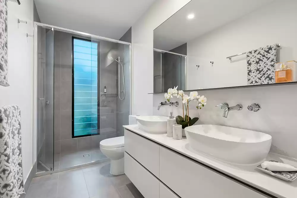 a bathroom with two sinks and a frameless bifold shower door