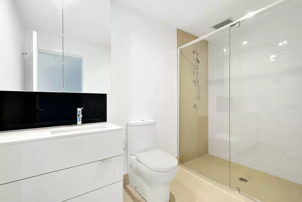 a glass shower door in a mostly white bathroom