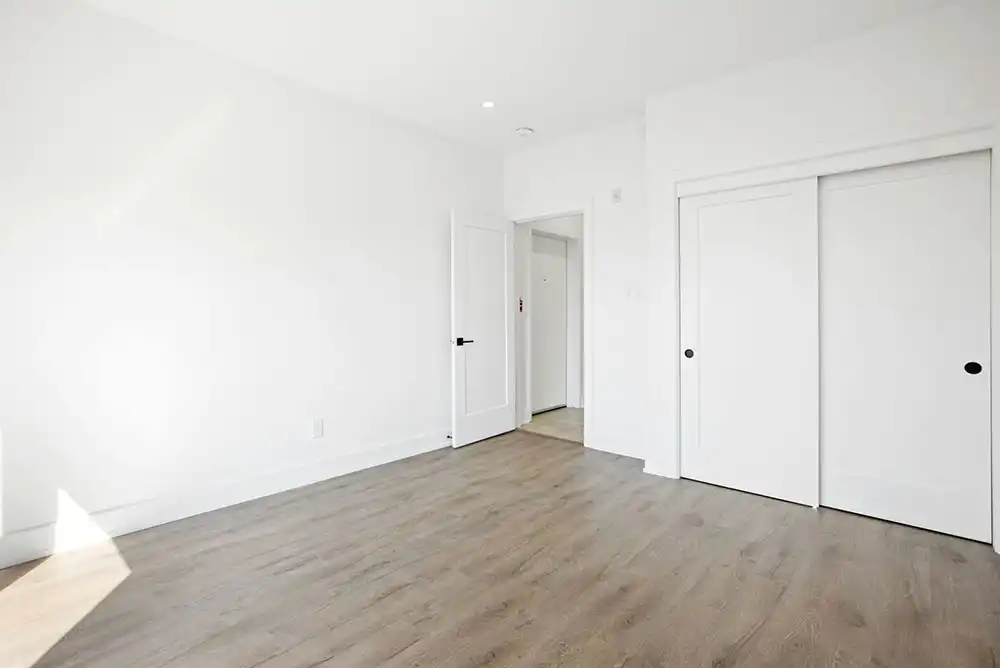 A bedroom with white walls and sliding closet doors.